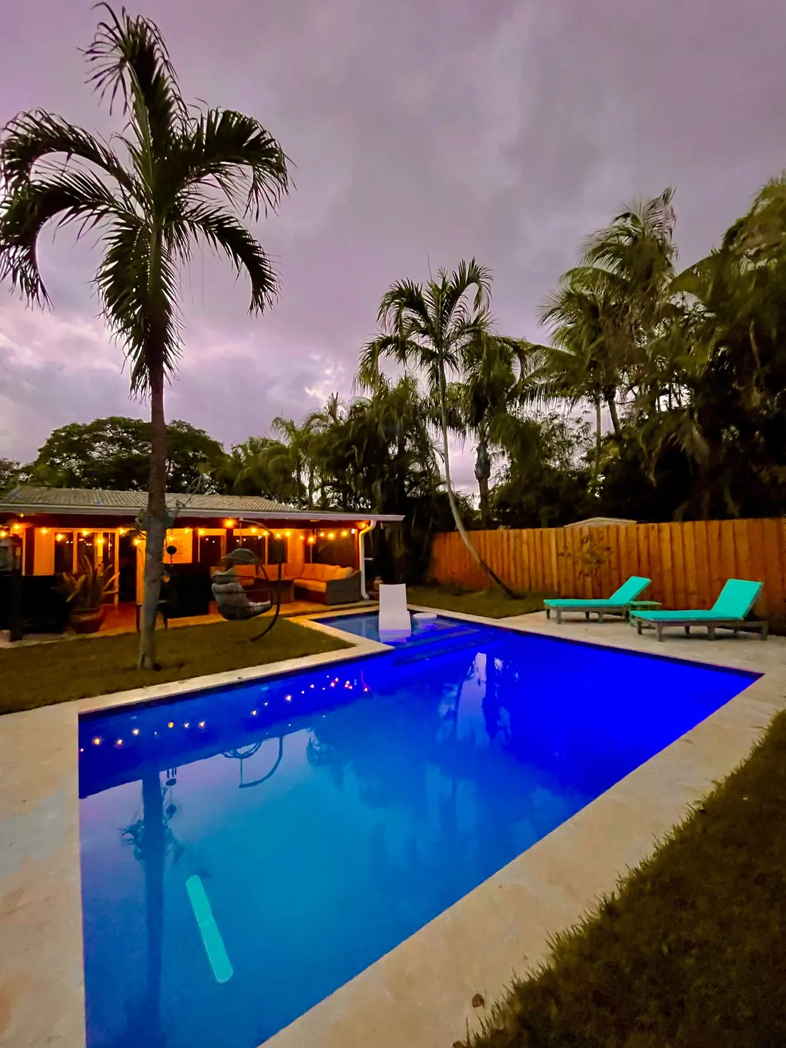 The pool at dusk with palms and warm string lights