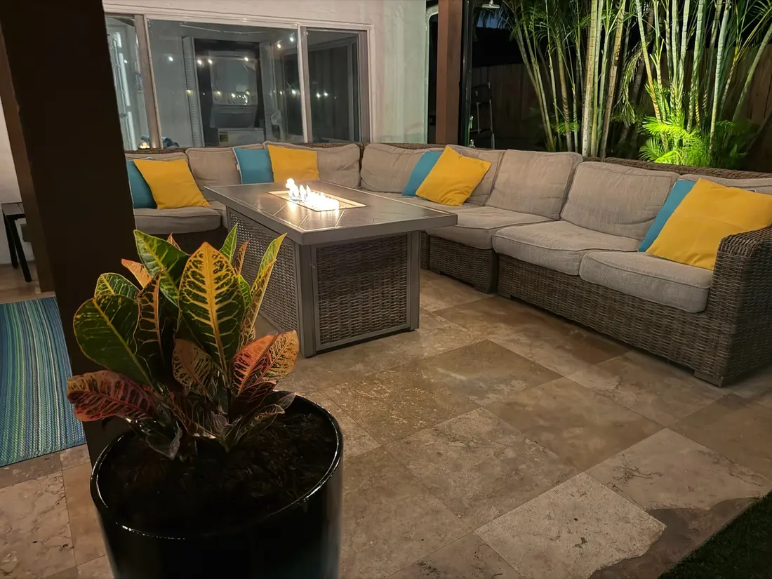 The patio lounge with the fire table lit and a potted croton in front