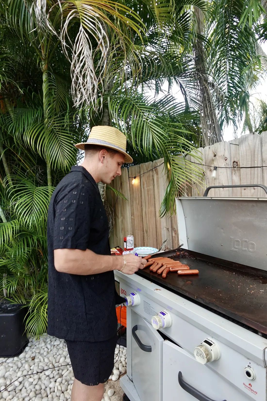 A guest cooking on the outdoor griddle in the palm-lined backyard