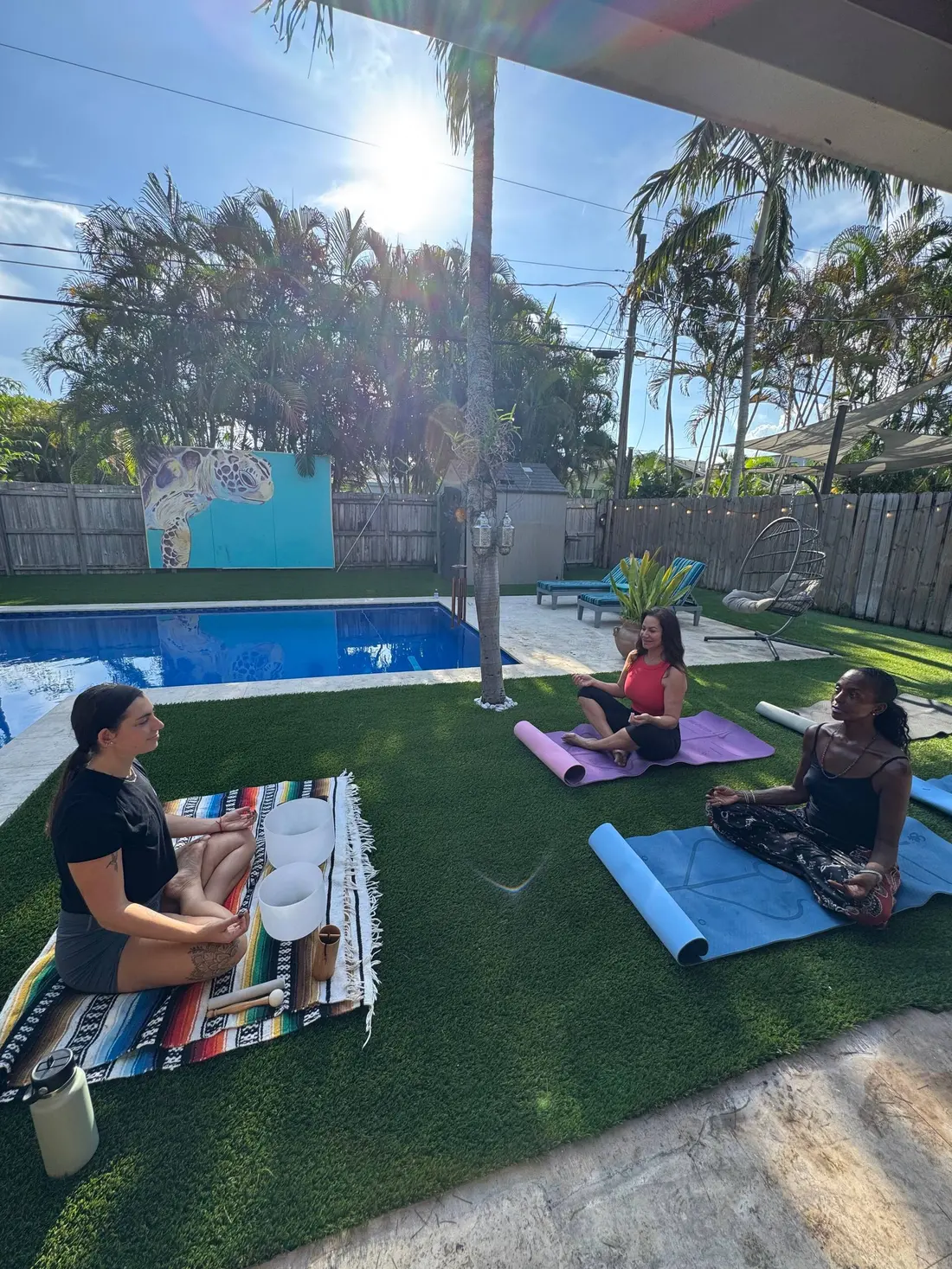 Guests doing yoga on the backyard lawn by the pool