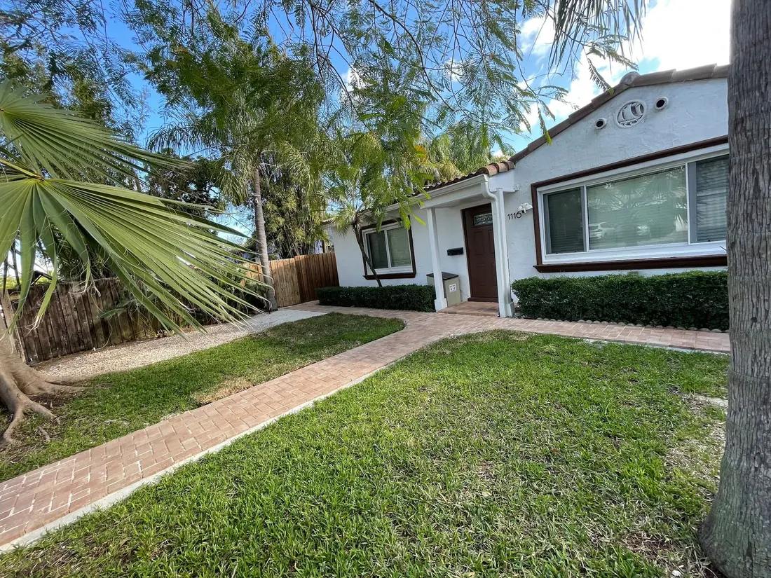The front of Turtle Nest Bungalow with its palms and turquoise trim