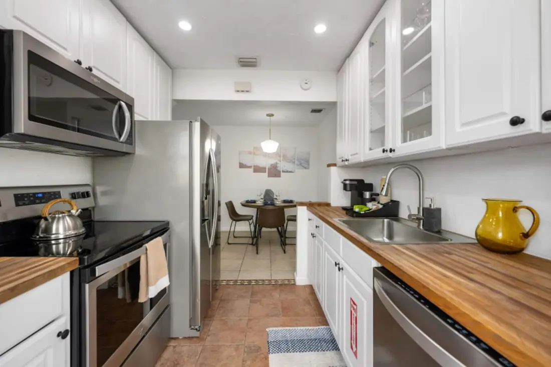 White kitchen with butcher-block island and stainless appliances