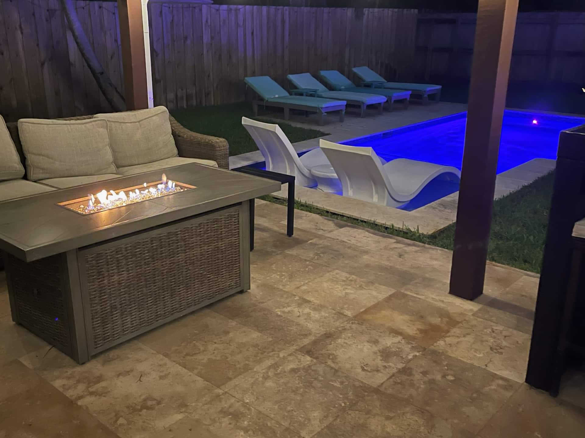 The fire pit and pool lit at night in the backyard