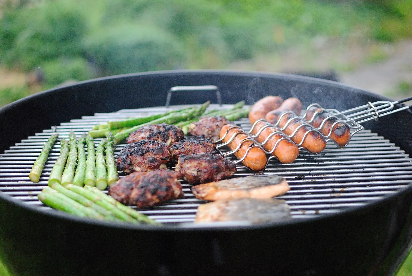 Burgers, sausages and vegetables cooking on a backyard barbecue grill