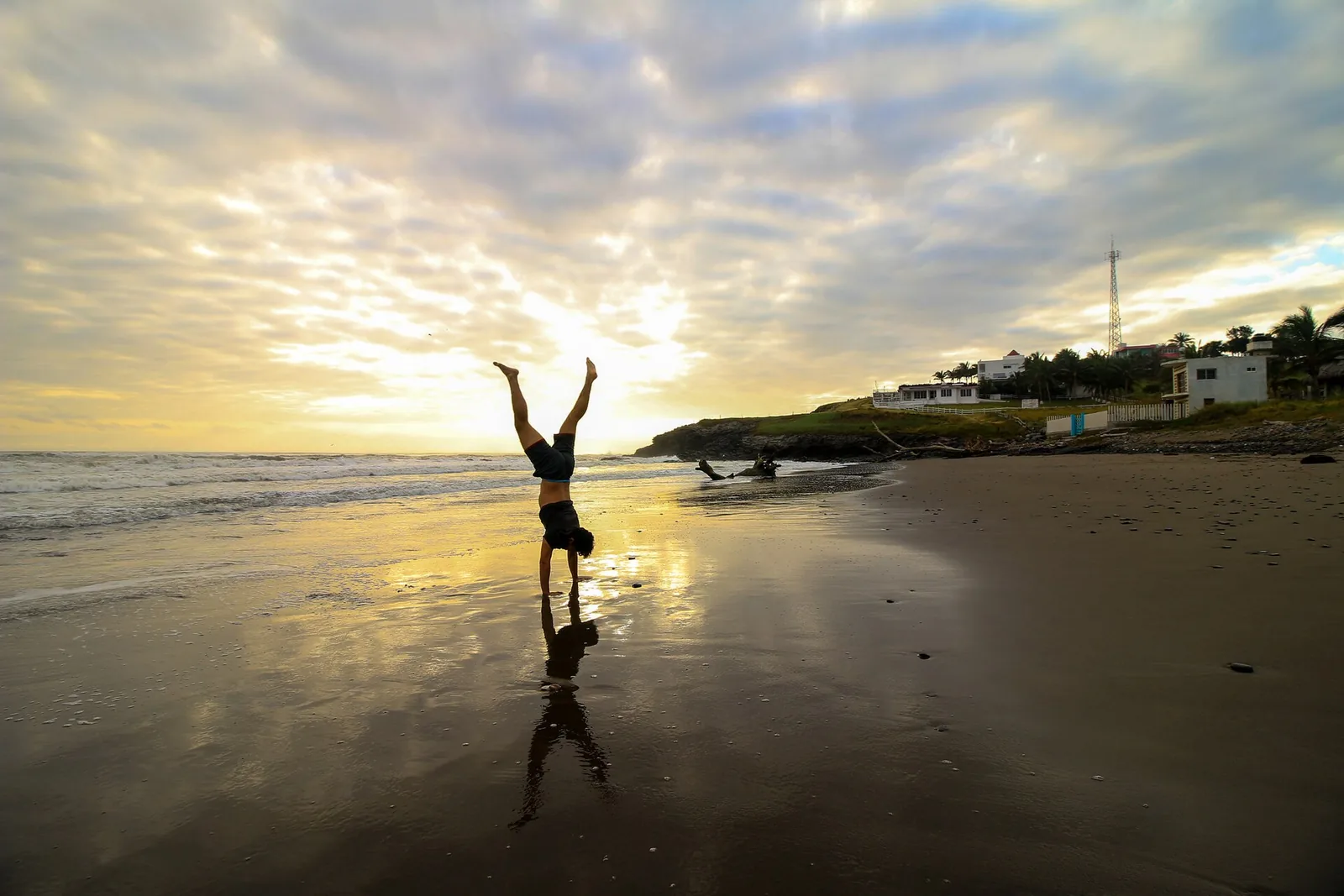 A person practicing yoga on the beach at sunrise