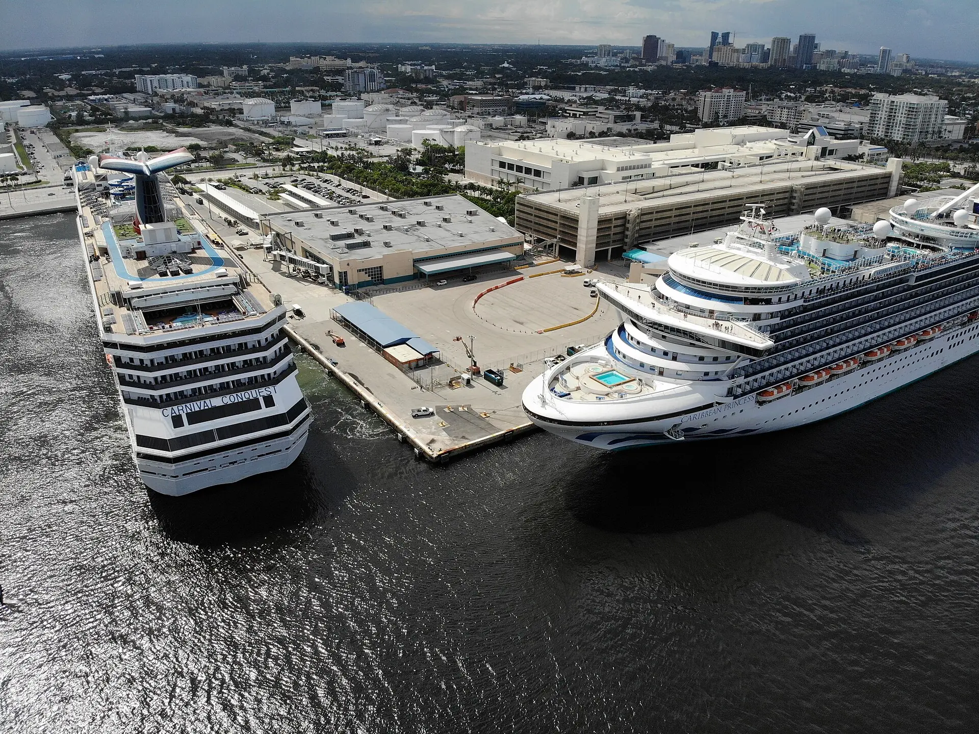 An aerial view of cruise ships docked at Port Everglades cruise terminal with the Fort Lauderdale skyline in the background