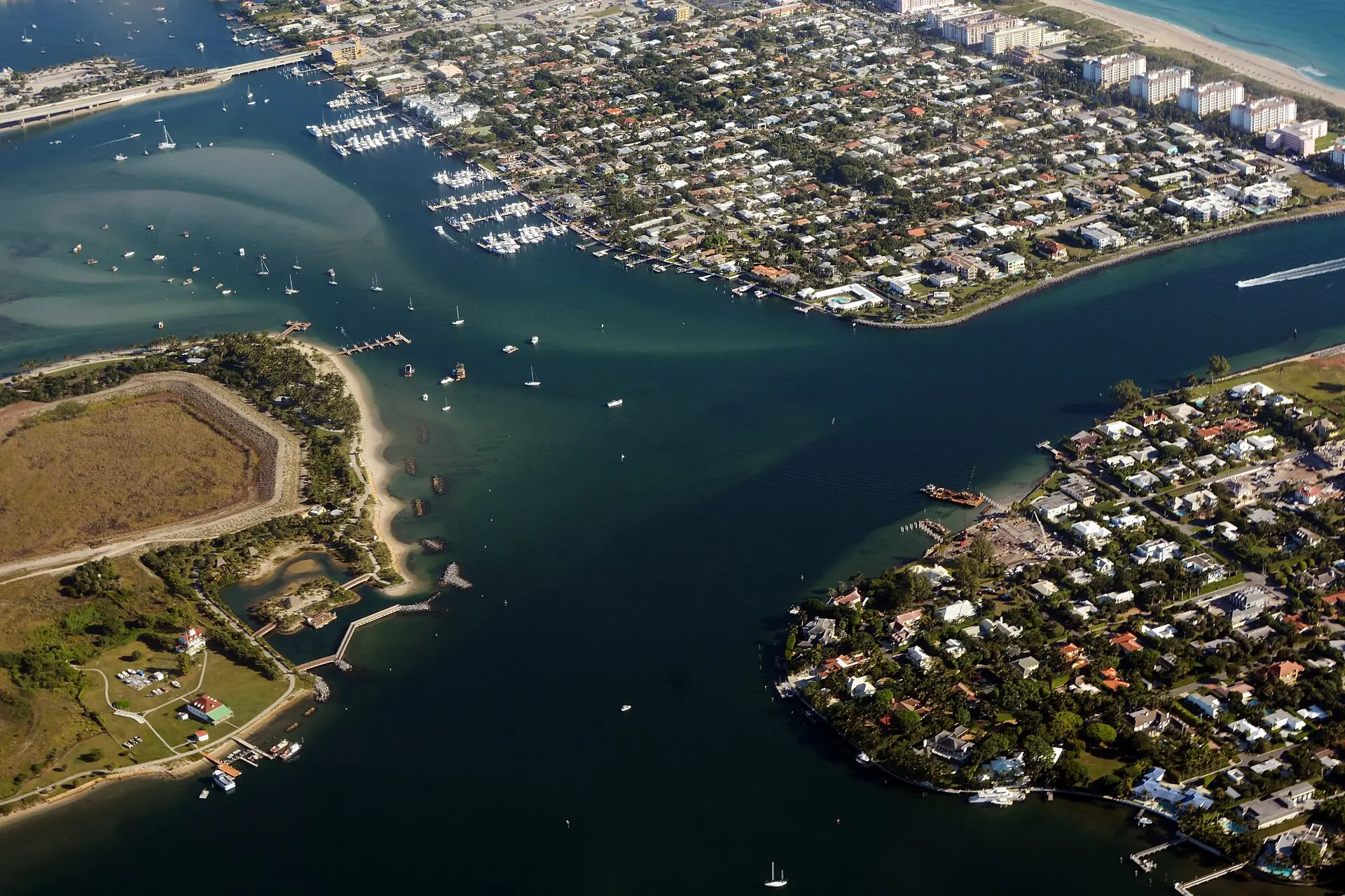 An aerial view of Jupiter Inlet and the surrounding residential communities and waterways in Palm Beach County, Florida, including the historic red Jupiter Inlet Lighthouse on the