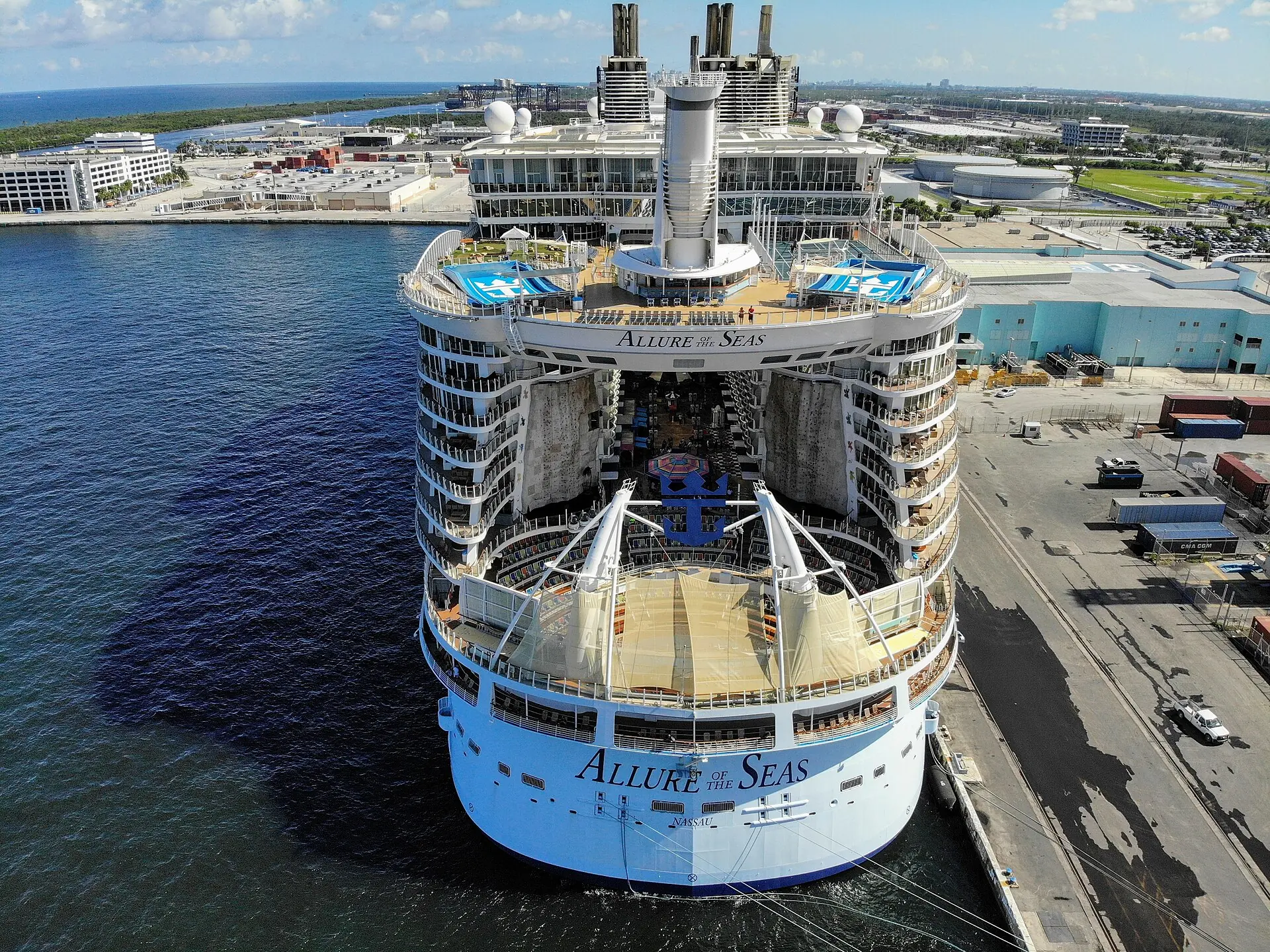 An aerial stern view of the massive cruise ship Allure of the Seas docked at a terminal in Port Everglades