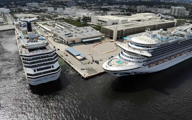 An aerial view of cruise ships docked at Port Everglades cruise terminal with the Fort Lauderdale skyline in the background