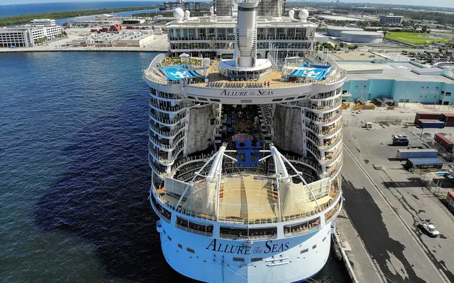 An aerial stern view of the massive cruise ship Allure of the Seas docked at a terminal in Port Everglades