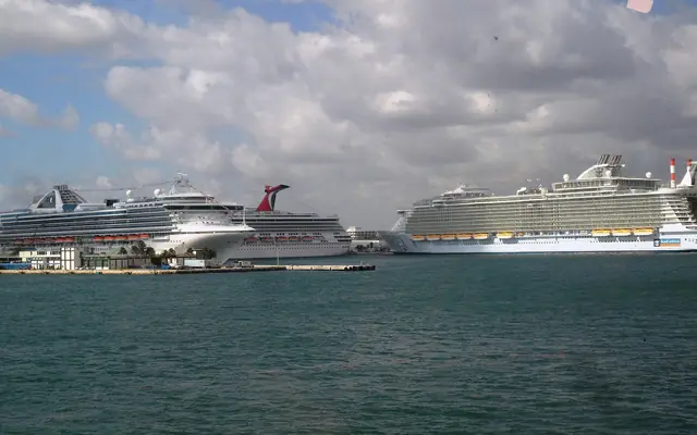 Port Everglades: multiple large cruise ships docked across a harbor basin under a partly cloudy sky