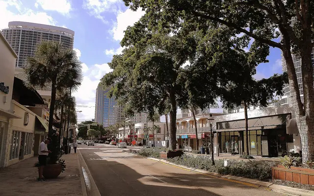Huizenga Plaza: a tree-lined boulevard lined with shops, restaurants, and palm trees with downtown high-rises in the background