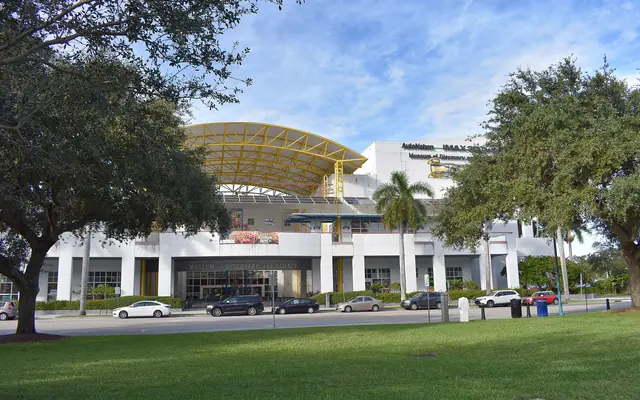 The exterior facade and entrance of the Museum of Discovery and Science in Fort Lauderdale, viewed across a grassy park and street