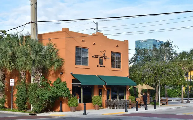 Old Fort Lauderdale Breakfast House restaurant with an orange facade, green awnings, and outdoor patio seating