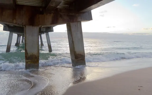 Lauderdale-by-the-Sea: waves washing under the fishing pier at sunrise