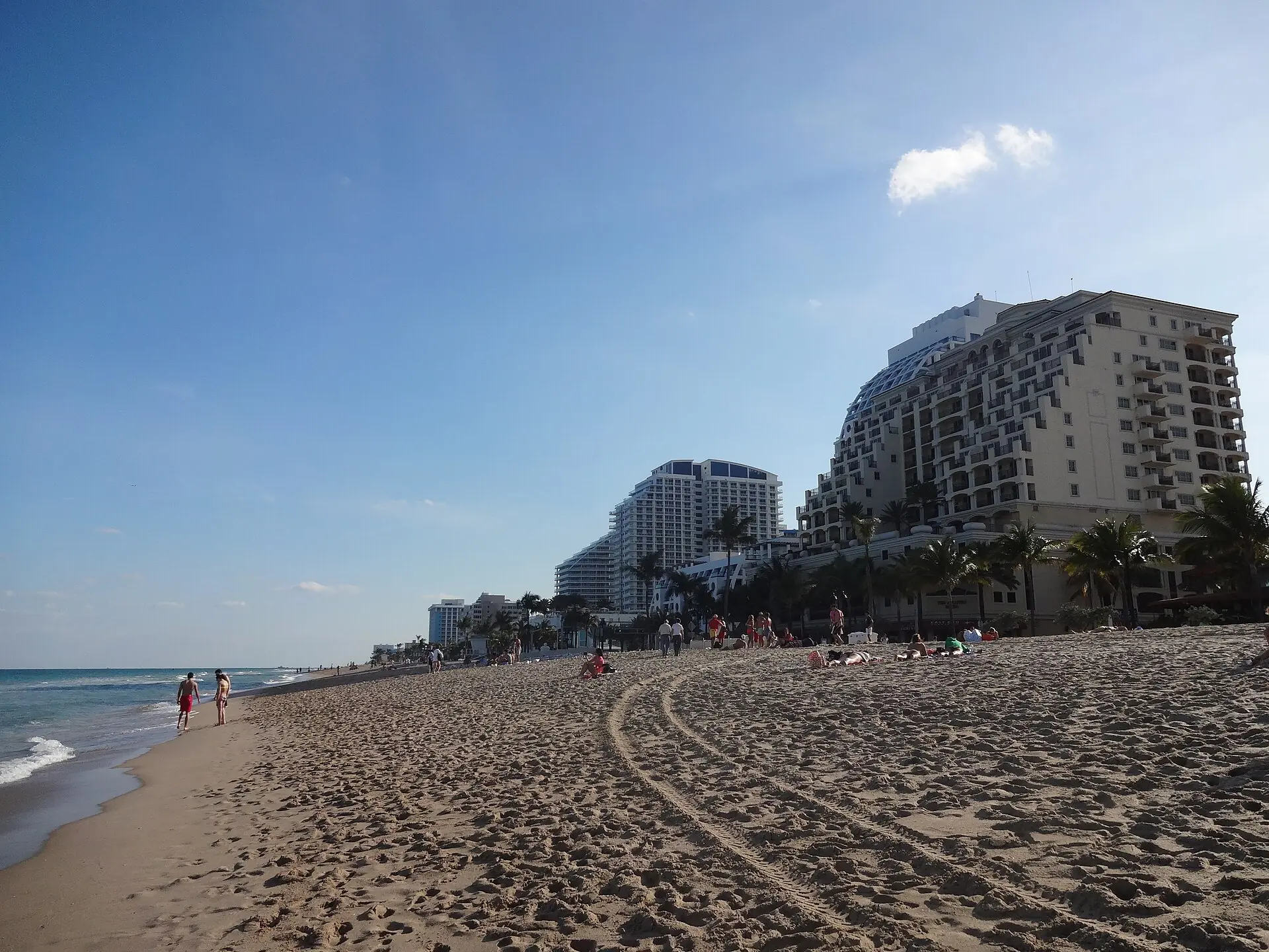 Fort Lauderdale Beach: a wide sandy ocean beach lined with luxury high-rise resort hotels and beachgoers under a blue sky