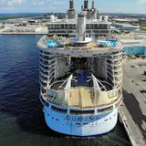 An aerial stern view of the massive cruise ship Allure of the Seas docked at a terminal in Port Everglades