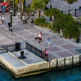 An elevated waterfront view of the promenade at Mallory Square in Key West with visitors and a street performer
