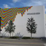 Exterior of the NSU Art Museum Fort Lauderdale building featuring a colorful dripping rainbow mural on its white modernist wall