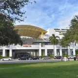 The exterior facade and entrance of the Museum of Discovery and Science in Fort Lauderdale, viewed across a grassy park and street